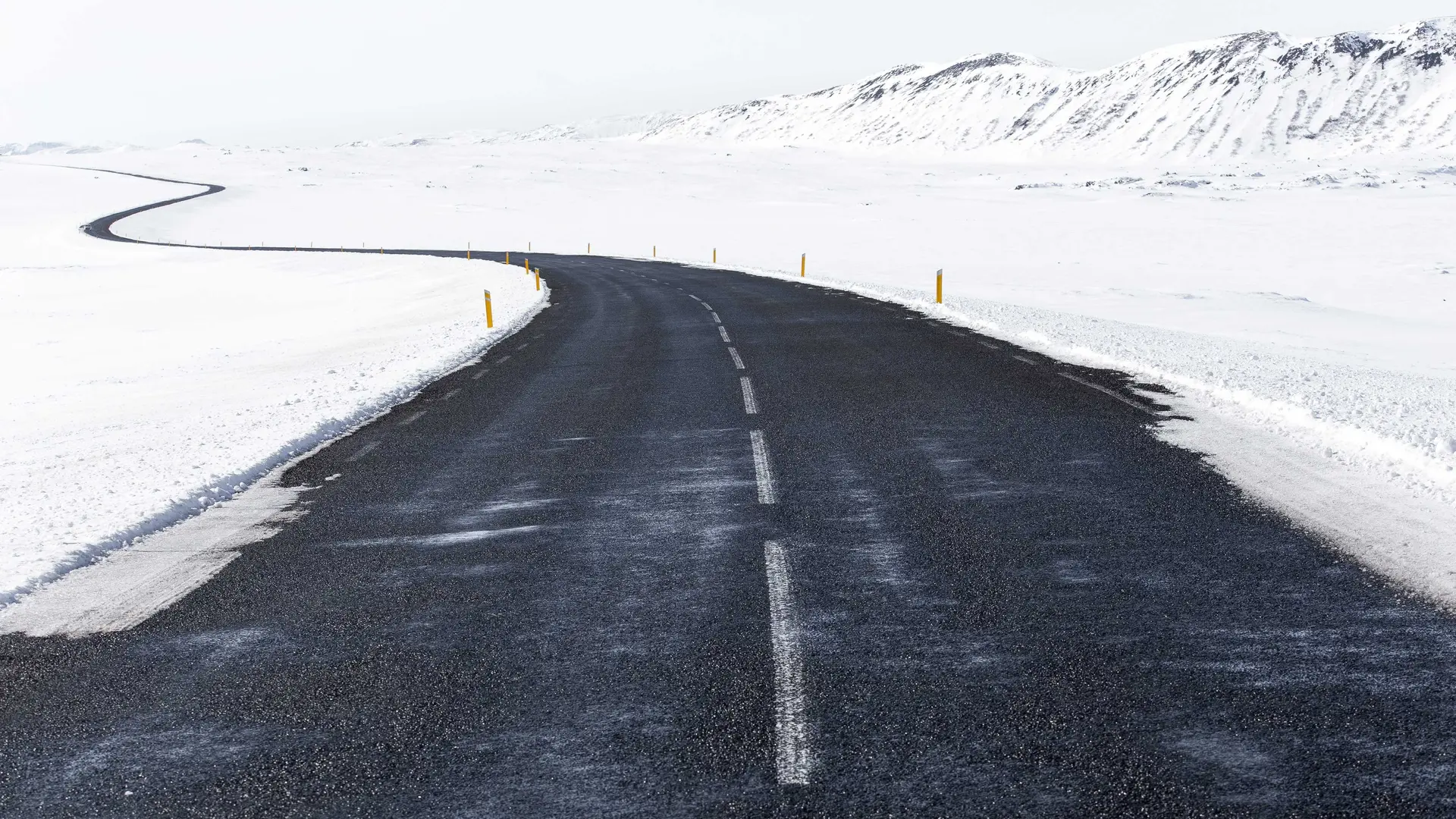 Wüstenstraße mit Schnee und Bergen im Hintergrund